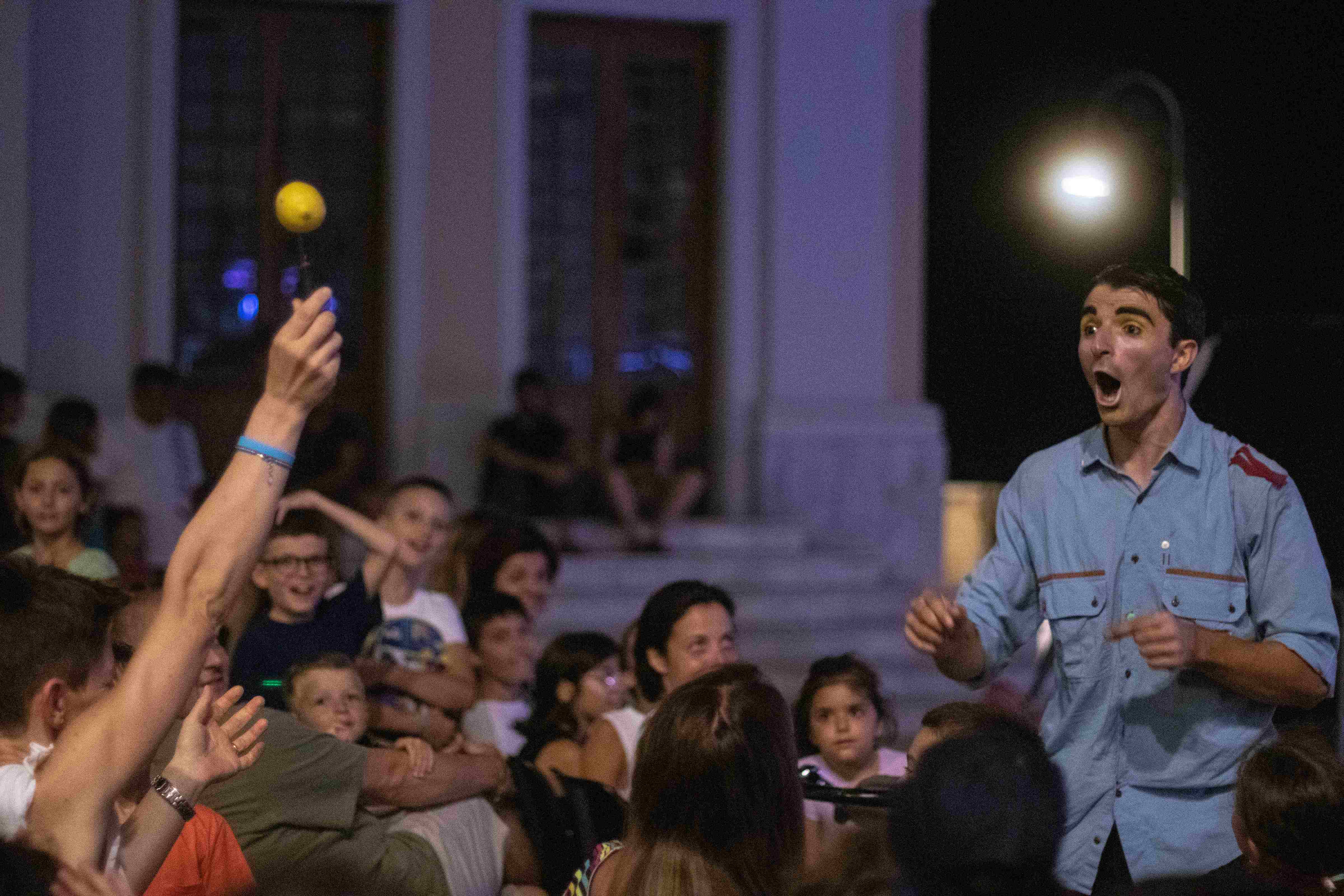 Un clown guarda sorpreso un limone infilzato in un coltello tra il pubblico.