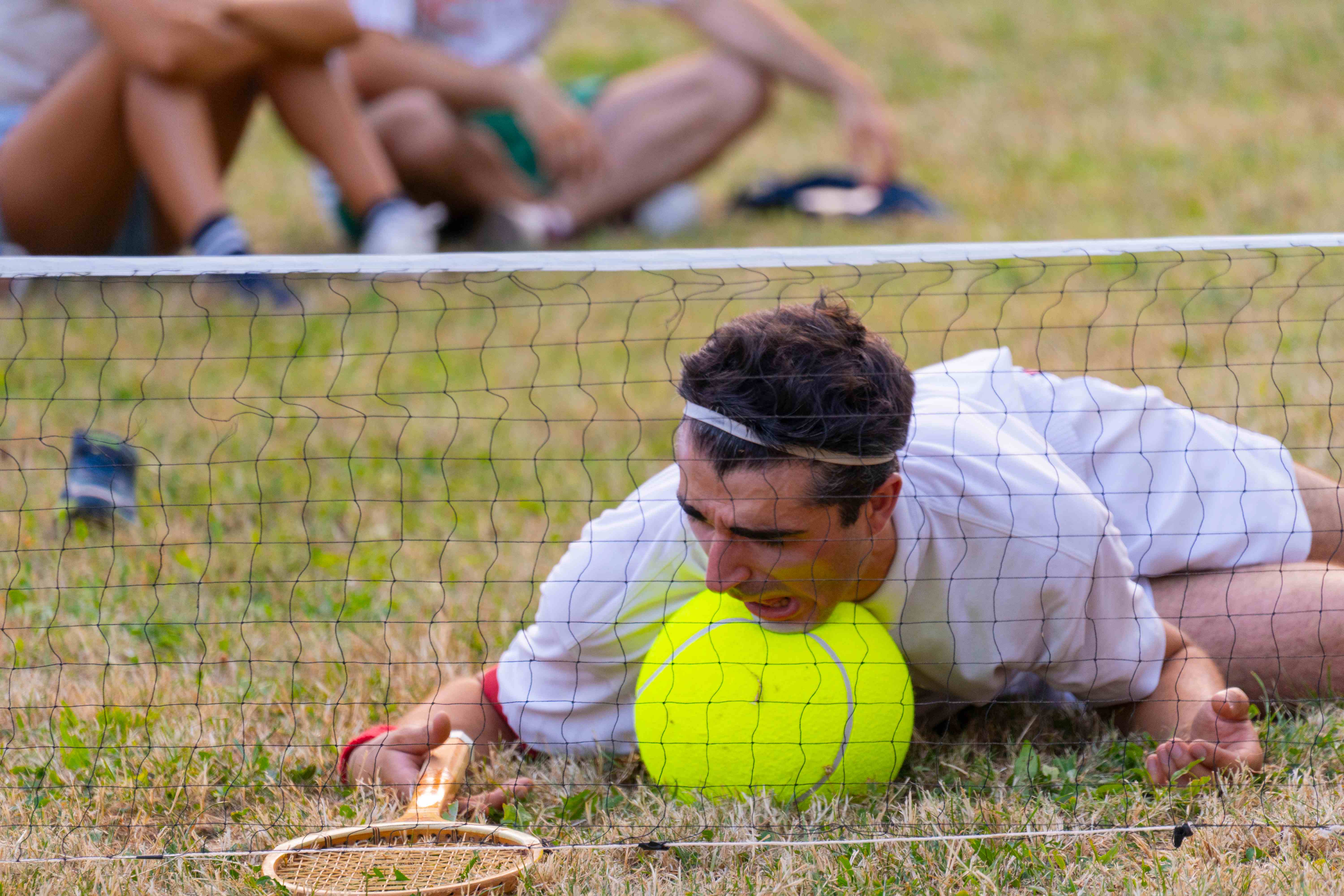 Un clown a terra disperato con una pallina da tennis gigante.