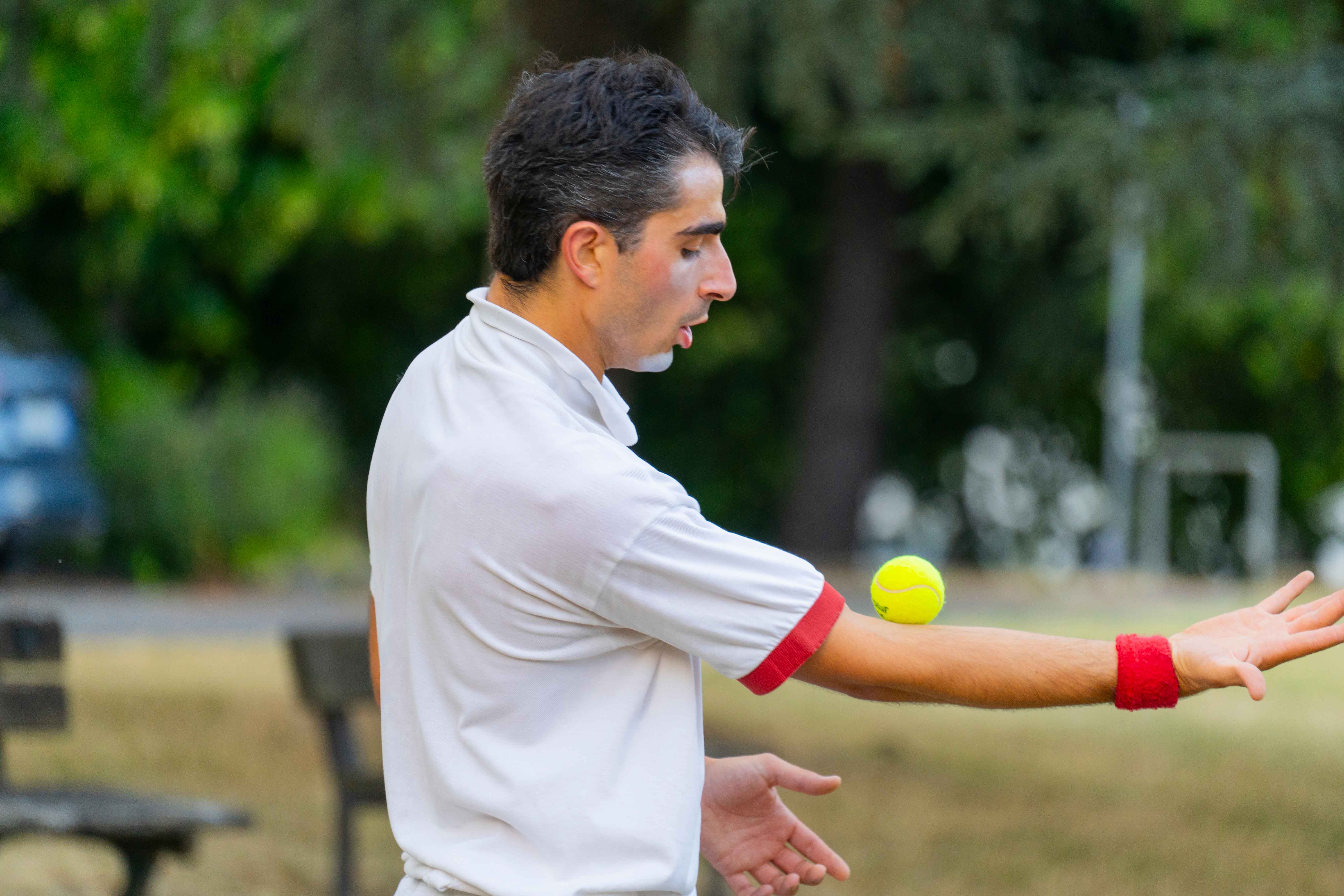Un clown tiene una pallina da tennis in equilibrio su un braccio.