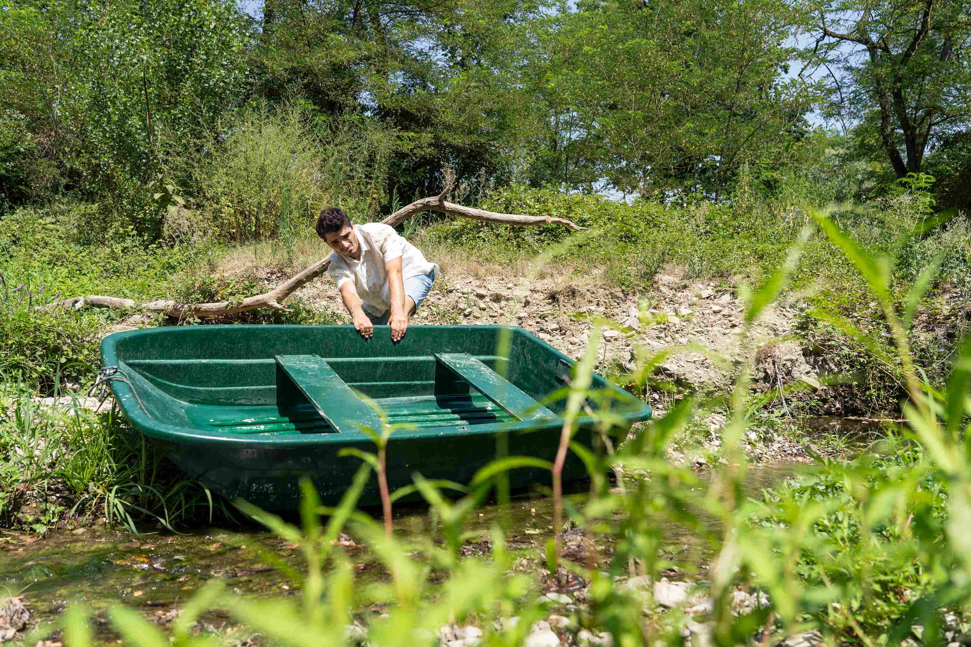 A character drags a small boat to shore.