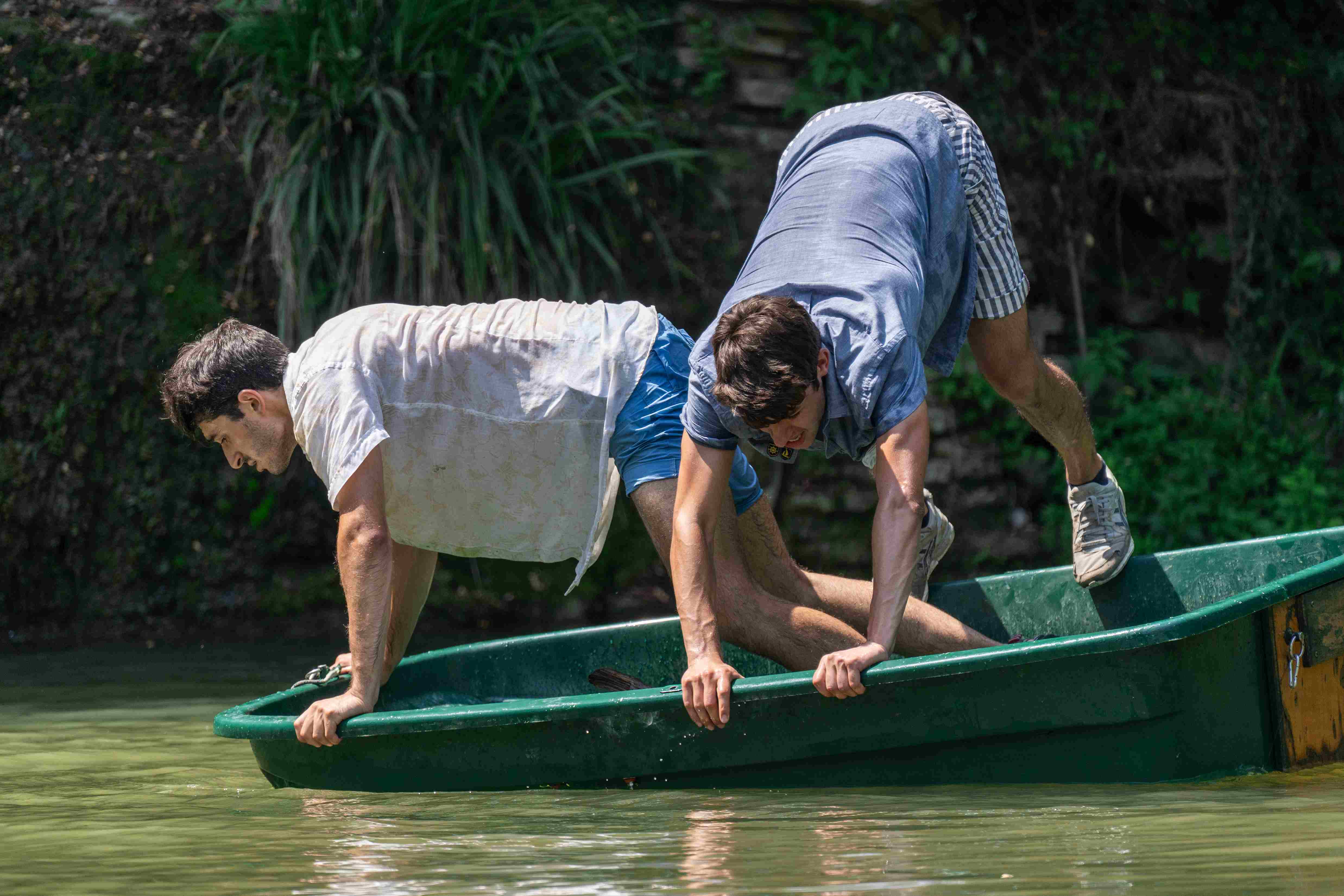 Due personaggi in equilibrio con mani e piedi sui bordi di una barchetta.