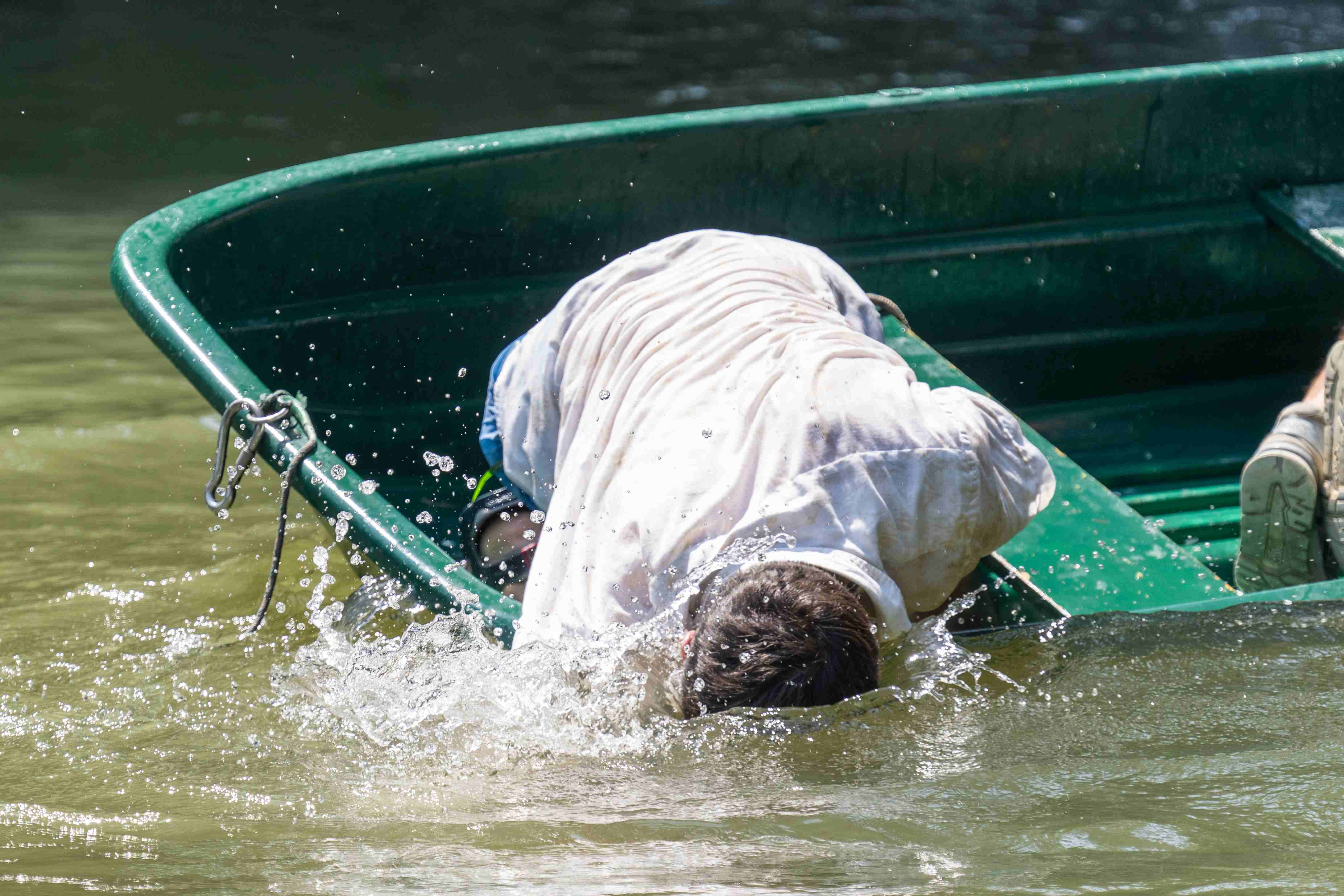 Un clown su una barca immerge la faccia nell'acqua.