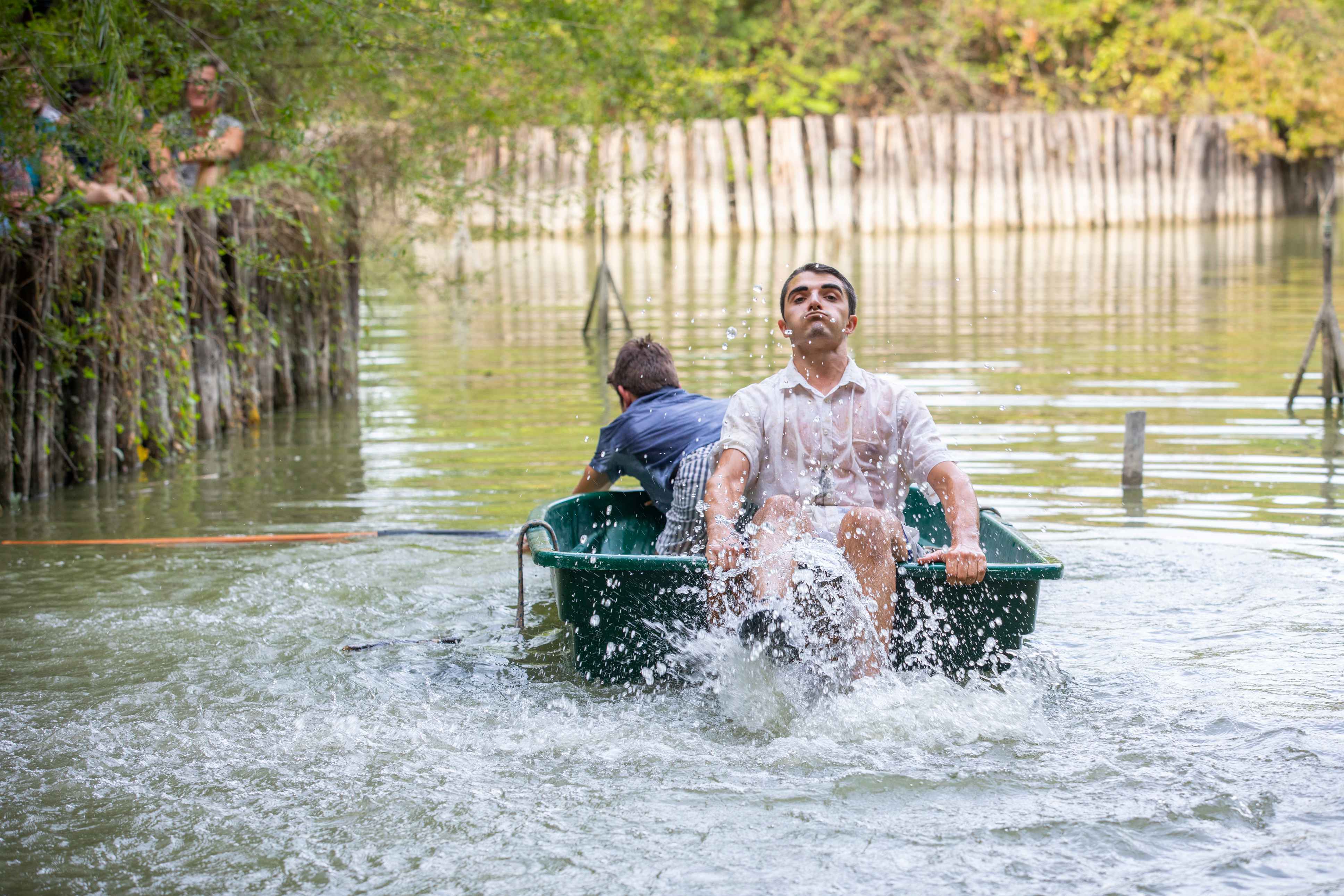 Un clown su una barca fa schizzi con i piedi in acqua.