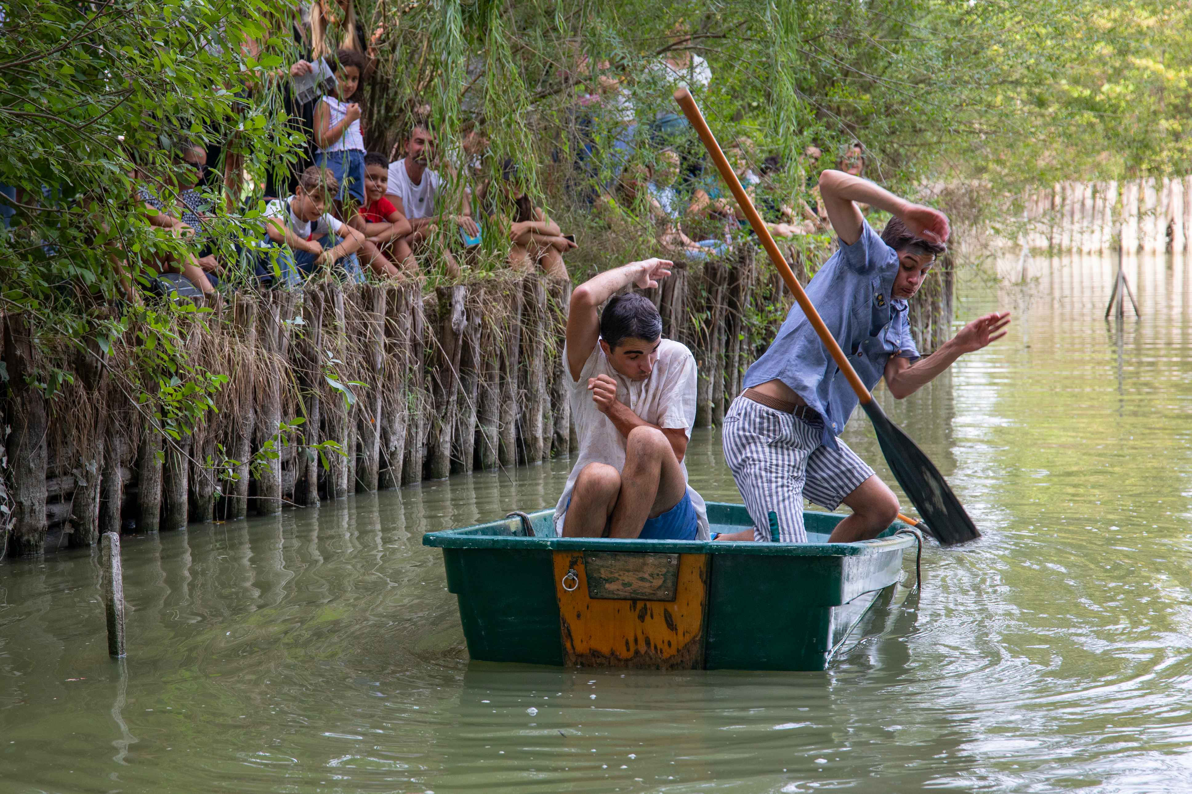Due clown su una barca si proteggono da un remo lanciato.